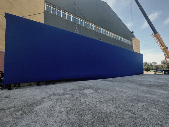 A blue-screen wall the full length of the hangar