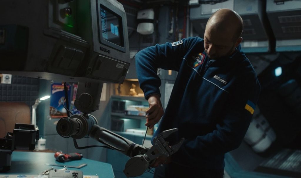 Film still from U Are the Universe: repairing the ship robot